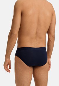 Marineblauwe katoenen slips met een zachte tailleband met reliëfbranding. Strak aansluitend ontwerp met minimale dekking aan de achterkant, gladde textuur.