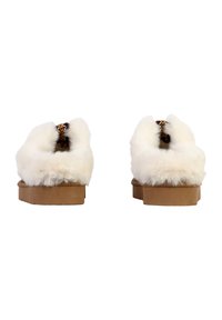 Hvide pels slippers med en tyk tan sål, der har et udskåret design og leopardmønstret detaljer på indersiden. Blød tekstur generelt.