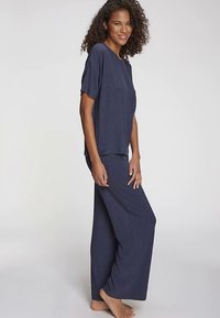 Ensemble lounge bleu marine composé de deux pièces : un haut à manches courtes et un pantalon à jambes larges, fabriqué en tissu texturé avec une coupe décontractée.