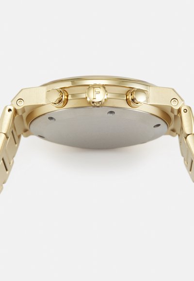 Orologio da polso dorato con cassa circolare piatta, due pulsanti e bracciale texturizzato. Il retro è liscio e metallico.