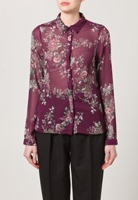 Sheer, long-sleeve blouse in deep purple with floral print in pink and green. Features a collar and button-up front.