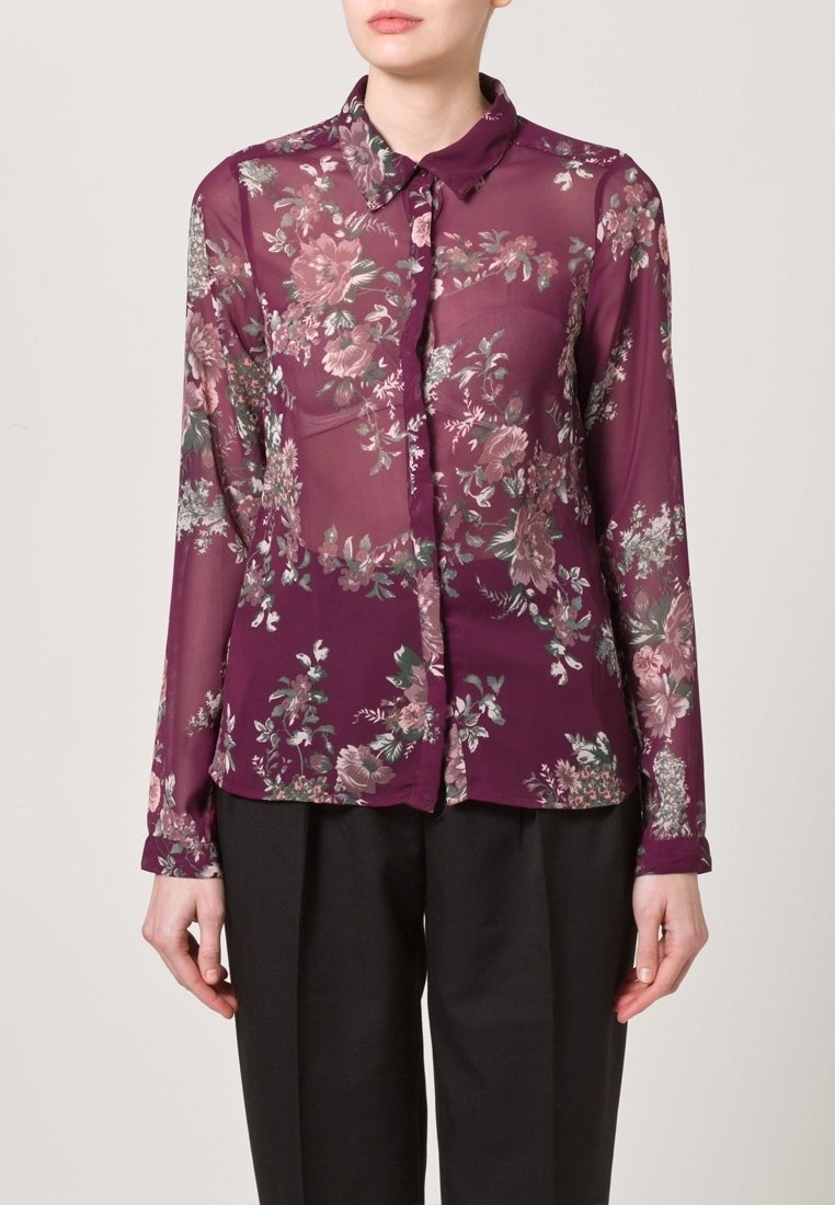 Sheer, long-sleeve blouse in deep purple with floral print in pink and green. Features a collar and button-up front.