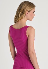 Fuchsia tank top with a ribbed texture, featuring lace-trimmed straps. The design is fitted and smooth, highlighting a clean silhouette.