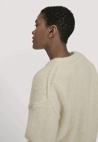 Crème gebreide trui met een ontspannen pasvorm, voorzien van een ronde halslijn, korte mouwen en een getextureerde ribbelstof langs het lichaam en de schouders.