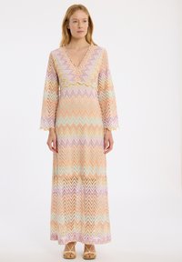 Robe maxi avec un décolleté en V, manches longues à cloche, fabriquée en tissu à motifs zigzag multicolores dans des teintes pastel, avec une coupe ample.