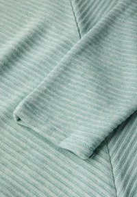 Tessuto rigato di un blu teal chiaro, con una consistenza morbida, caratterizzato da una manica piegata e dettagli di cucitura inclinati.