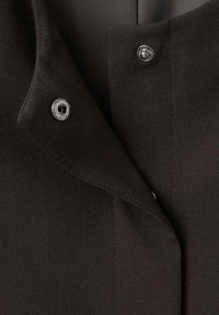 Zwarte op maat gemaakte jas met een reverskraag, voorzien van zilverkleurige metalen knopen en een gladde stoftextuur. Fijne stiksels zichtbaar.