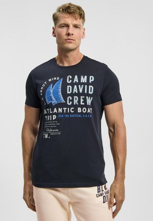 Marineblaues Baumwoll-T-Shirt mit weißem und blauem Textdruck sowie Segelboot-Grafiken. Rundhalsausschnitt, kurze Ärmel, legerer Schnitt.