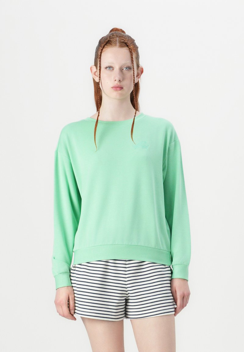 Felpa verde menta con maniche lunghe e orlo a coste, abbinata a pantaloni corti a righe bianche e blu navy. Il materiale sembra morbido e leggero.