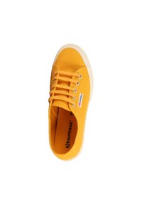 Sneaker di tela gialla con punta rotonda, suola in gomma bianca e design classico con lacci. Presenta un'etichetta con il logo sul lato.