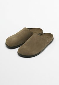 Bruna mockaskor med slät yta, rund tå och en låg svart sula. Enkelt design utan synlig hårdvara eller accenter.