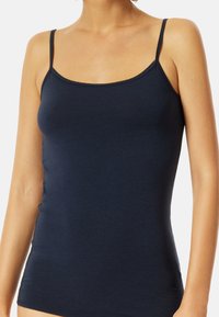 Navy blue tank top with thin straps, made from smooth fabric. Features a fitted design and a rounded neckline with a contrasting trim.