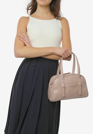 Borsa a mano in pelle rosa chiaro con manici doppi, forma arrotondata, dettagli di cucitura sottili e chiusura con zip. Indossata con un top aderente e una gonna plissettata.