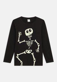 Black long-sleeve shirt featuring a white skeleton graphic. The design includes a smiling skull and bone details, with a crew neck.