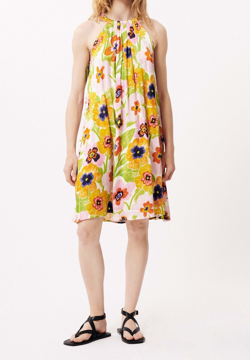 Robe à bretelles nouées au cou avec un motif floral vif multicolore sur un fond rose clair ; coupe ample avec un ourlet longueur genou. Sandales noires incluses.