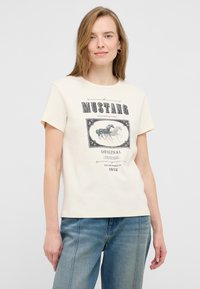 Beżowa bawełniana koszulka z krótkim rękawem, z nadrukiem graficznym przedstawiającym galopujące konie w stylu vintage oraz napisem "MUSTANG".