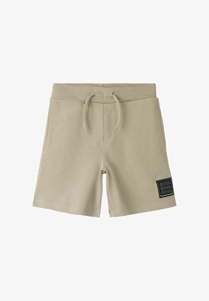 Short en coton beige avec taille élastique, cordon de serrage, poches latérales et écusson noir indiquant "COOL COOL COOL" sur la jambe gauche.