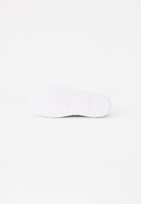 Suola di sneaker bianca con un motivo di grip testurizzato, caratterizzata da una finitura liscia e disegni geometrici in rilievo per la trazione.