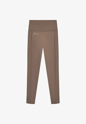 Leggings marroni a vita alta con un piccolo logo bianco scritto a mano sull'anca sinistra su sfondo bianco.