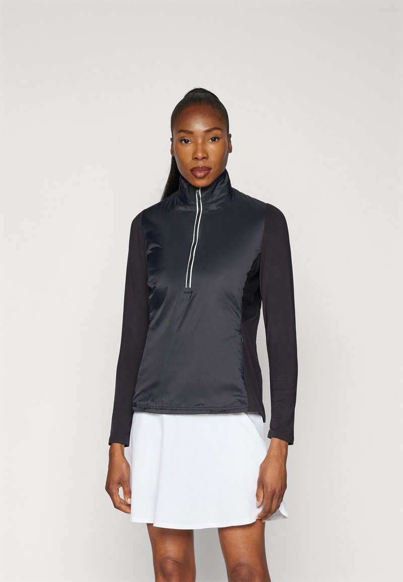 Černá sportovní vesta s vysokým límcem, předním zipsovým uzávěrem na půl, a dlouhými černými rukávy. Hladký povrch s kontrastním bílým zipem.