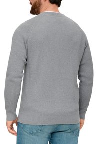 Gray ribbed sweater with long sleeves, round neck, and a fitted bottom hem, paired with light blue denim jeans.