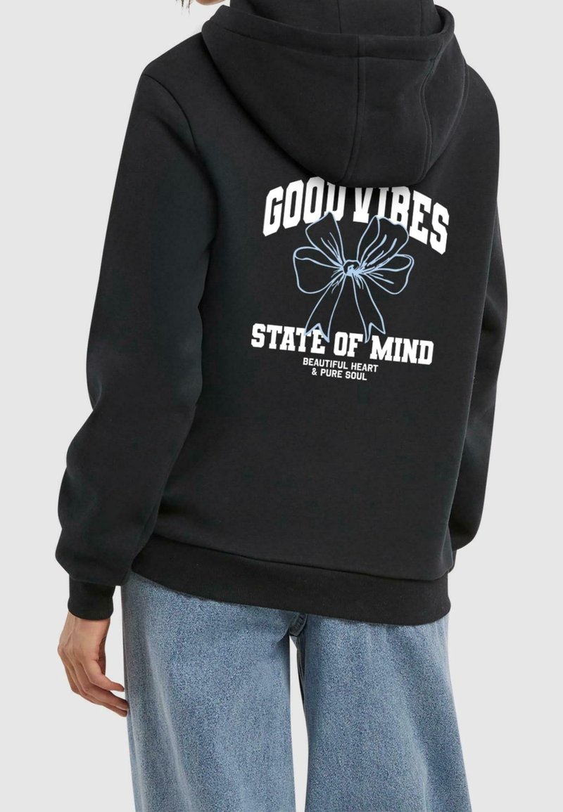 Sweat à capuche noir porté par une personne, avec texte blanc "GOOD VIBES STATE OF MIND" et un graphisme nœud bleu contour au dos.