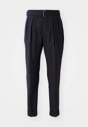 Pantalons bleu marine en tissu léger, dotés de plis, d'une ceinture avec une boucle métallique et de bas roulés aux chevilles.