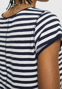 T-shirt a righe navy e bianche caratterizzato da maniche corte, scollatura rotonda e dettagli di cucitura visibili lungo le cuciture. Tessuto di cotone morbido.