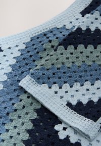 Bawełniany koc szydełkowy z gradientem niebieskich i zielonych odcieni w wzorze plastra miodu, z obramowaniem w jasnoniebieskim kolorze.