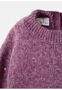 Mysig lila stickad tröja med rund halsringning och ribbad kant, prydd med en fläckig struktur och små dekorativa detaljer här och där.