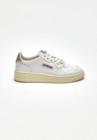 Sneaker bianco in pelle con superficie texture, suola leggermente beige e sottili dettagli dorati sul tallone. Presenta un design perforato sulla punta.