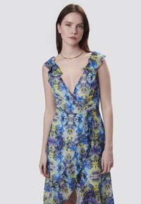 Blumenkleid mit tiefem Ausschnitt,-Rüschensäumen und mehrfarbigem Muster in Blau-, Lila- und Gelbtönen. Weicher, leichter Stoff.