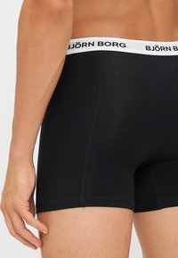 Black boxer briefs made of soft fabric with a white waistband featuring "BJÖRN BORG" logo, showcasing a fitted design and seamless edges.