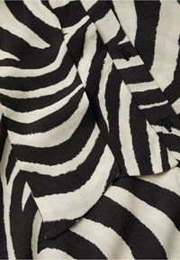 Tissu à rayures zébrées noir et blanc avec des boutons visibles et une vue en gros plan des couches superposées.