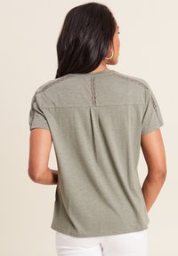 Olijfgroen t-shirt met korte mouwen en kantdetails langs de schouderranden, met een relaxte fit. Gladde, lichte stof.