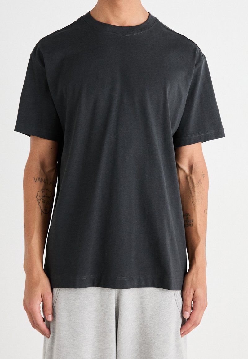 Dunkelgraues Baumwoll-T-Shirt mit kurzen Ärmeln, einem runden Ausschnitt und einer lässigen Passform. Minimalistisches Design ohne sichtbare Muster oder Akzente.