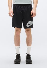 Svarta löparshorts med stretchig midjeresår och silverfärgad "RUN"-grafik tillsammans med Nike-logotypen. Bärs med vita strumpor och svarta sportskor.