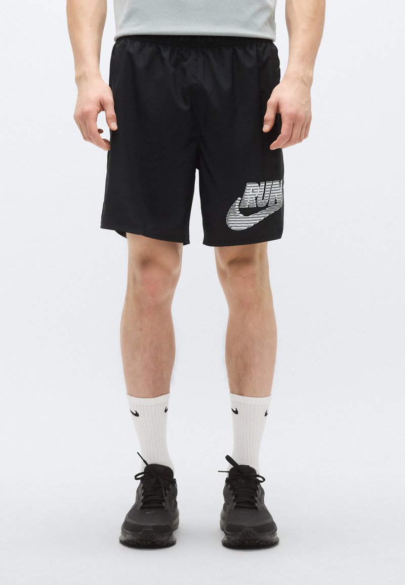 Schwarze Laufshorts mit elastischem Bund und silbernem "RUN"-Schriftzug neben dem Nike-Logo. Kombiniert mit weißen Socken und schwarzen Sportschuhen.