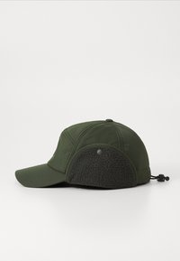 Grøn cap med en let buet skygge, der har en blød, mørk fleece-øreklap på siden. Fremstillet af et tekstureret, letvægtsstof.