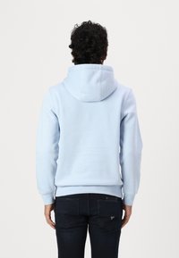 Ανοιχτό μπλε φούτερ με υφή, κουκούλα με κορδόνι και ribbed μανίκια. Συνδυασμένο με σκούρο μπλε τζιν που διαθέτει πίσω τσέπες.