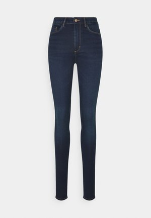 Skinny jeans made of dark blue denim. Features include a front button closure, five-pocket design, and stitching accents.