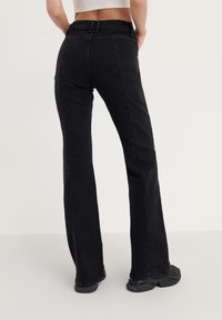 Sorte vide bukser med høy midje, laget av denim. Har sidelommer og en glatt, ensfarget tekstur. Ingen synlige mønstre eller detaljer.