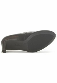 Scarpa nera in pelle con tacco alto e design elegante. La suola è in gomma texturizzata, con branding in rilievo e un tacco curvo e affusolato.
