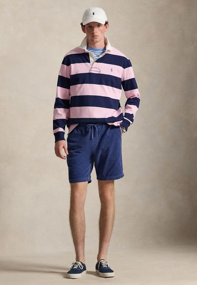 Μακρυμάνικο πόλο από ριγέ βαμβάκι σε σκούρο μπλε και ροζ, σετ με σκούρο μπλε σορτς. Συνδυάζεται με λευκό καπέλο και σκούρα μπλε παπούτσια. Καθημερινή, άνετη εφαρμογή.