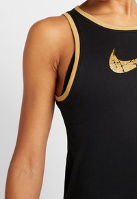 Canottiera nera con logo Nike dorato screpolato, caratterizzata da un collo tondo e dettagli in oro a contrasto lungo le aperture delle braccia e il colletto.