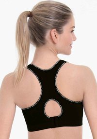 Brasile sportivo nero con design a racerback e un taglio circolare, dettagli del logo a contrasto lungo i bordi e forma aderente.