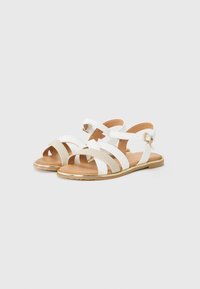 Hvite sandaler med tre brede stropper med metallisk gullfarge, flate såler og spenne, designet for hverdagsbruk.