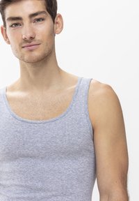 Grå bomullstanktop med breda axelband, figurnära design och mjuk textur. Tyget har en lätt melerad nyans för extra detalj.