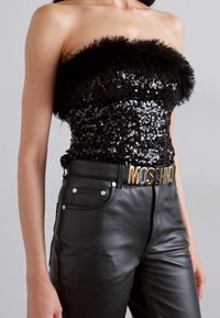 Sort, pailletbelagt top uden stropper med en fjerkrave, parret med tætsiddende sorte læderbukser og et Moschino-bælte med guldaccenter.