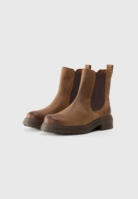 Bottes en cuir marron jusqu'à la cheville avec des panneaux élastiques sur les côtés, bout arrondi et semelle en caoutchouc texturé. Elles sont dotées d'onglets de tirage pour un enfilage facile.